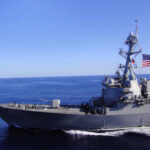 Iranian Ship Seizure Sparks Global Tensions A naval destroyer sailing in the ocean with an American flag