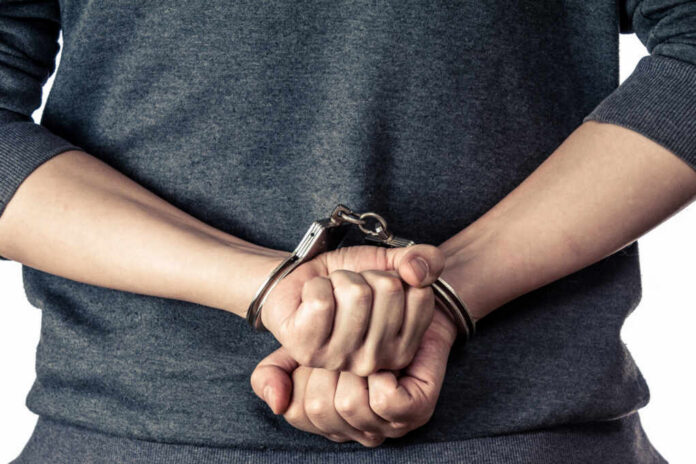 shutterstock_124782544.jpg Hands in handcuffs, showing a clenched fist