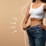 Big Pharma THREATENED by One-Time Obesity Solution Woman showcasing weight loss by holding oversized jeans