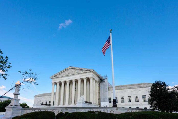 shutterstock_2527222311.jpg U.S. Supreme Court building with American flag and blue sky