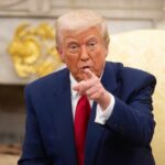 Trump Defiant as Iran Ceasefire Nears End A man in a blue suit and red tie pointing while seated