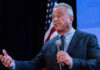 RFK Jr. Targets SSRIs in Federal Campaign A man speaking into a microphone at a podium with an American flag in the background
