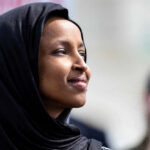 VP Vance’s Bold Claim: Omar Under Investigation! Woman wearing a black hijab looking thoughtfully into the distance
