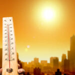Unbearable Heat Wave: A Climate Warning A thermometer held against a sunset city skyline