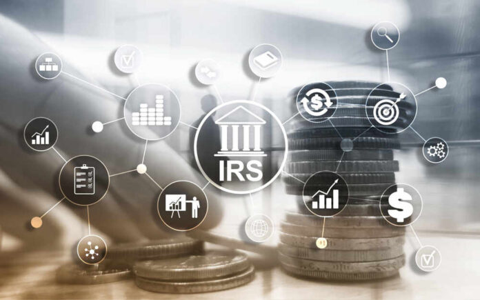 A hand reaching towards stacks of coins with financial icons surrounding the IRS logo