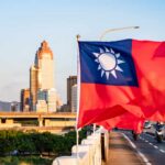 Taiwan flag waving in front of a city skyline during sunset