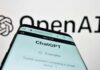 Close-up of a smartphone displaying the ChatGPT interface with the OpenAI logo in the background
