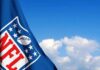 NFL flag waving against a blue sky with clouds