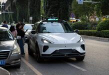 An autonomous vehicle on a city street with people nearby