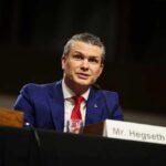 Man in a blue suit speaking at a government hearing