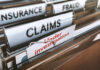 Folders labeled with insurance terms, highlighting a claim under investigation