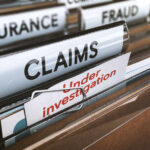 Folders labeled with insurance terms, highlighting a claim under investigation