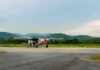 Small propeller plane on rural runway with hills in the background