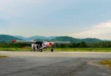Small propeller plane on rural runway with hills in the background