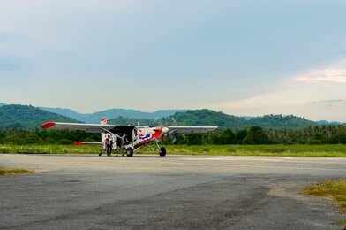 Small propeller plane on rural runway with hills in the background