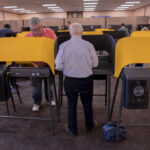 Election Night Lies? Scoreboard Keeps Shifting Individuals casting votes at a polling station with electronic voting machines