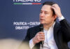 Trillionaire? Musk’s Pricey Mirage Individual speaking at a conference, holding a microphone