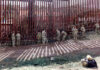 Military personnel working on a border fence with barbed wire