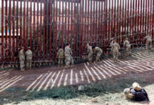 Military personnel working on a border fence with barbed wire