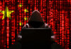 Foreign Grip On France’s Spies A hooded figure sitting in front of a laptop with a red digital background