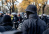 Asylum Flashpoint Ignites Belfast Chaos A crowd of masked individuals facing law enforcement in an autumn setting