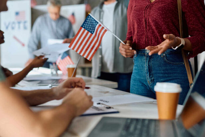 shutterstock_2433504143 People participating in a voting event with American flags and paperwork