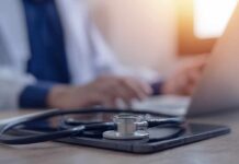 Doctors Warn: Standing Sex Backfires A stethoscope resting on a tablet with a blurred medical professional in the background typing on a laptop