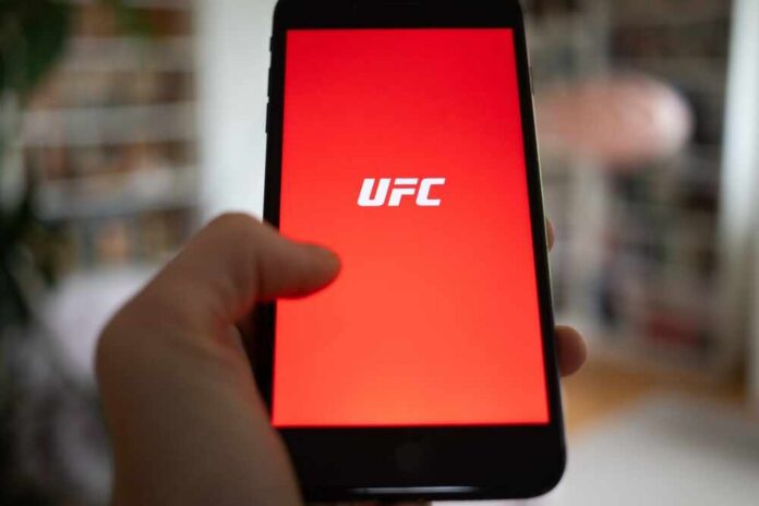 Person,Opening,Ufc,App,On,A,Phone Hand holding smartphone with red app screen