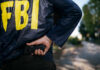 FBI agent gripping handgun near waistband outdoors