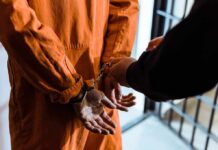 Pastor-Instructor Exposed — Chilling Trail Since 2012 Prisoner in orange jumpsuit handcuffed by officer