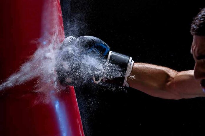 Boxer’s gloved fist strikes a red punching bag, sending chalk dust into the air