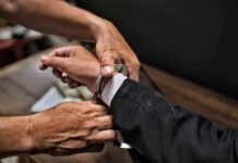 Hospital Millions Vanish—Accountant Caught hands placing handcuffs on a suited person's wrists