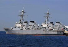 Iran’s Chilling Promise: Nowhere Safe Three gray naval destroyers docked side by side at a pier