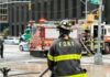 Firefighter in FDNY uniform overseeing emergency response at a city intersection
