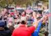 Crowd of people waving small American flags at a public event