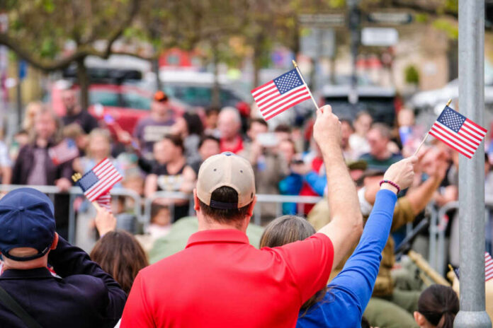 Crowd of people waving small American flags at a public event
