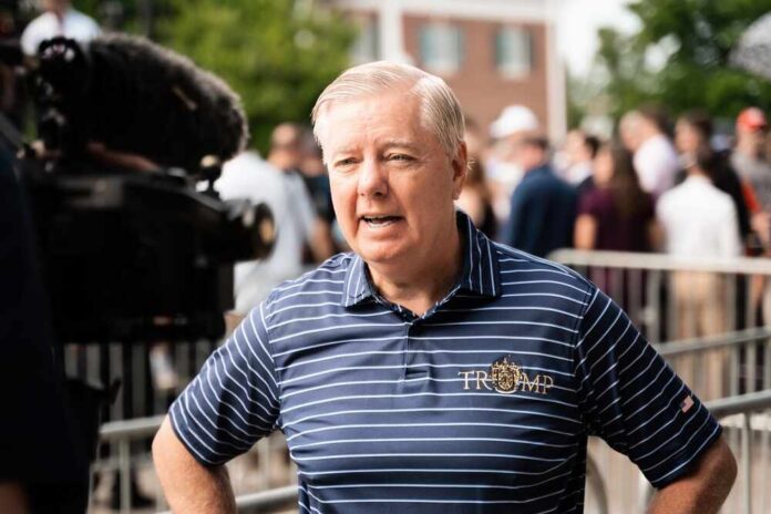 A man in a striped shirt speaking during a media interview at an outdoor event