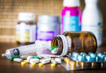 DOJ Pressure Mounts: Pill Network Exposed? Medicine pills and syringe on table with brown bottle